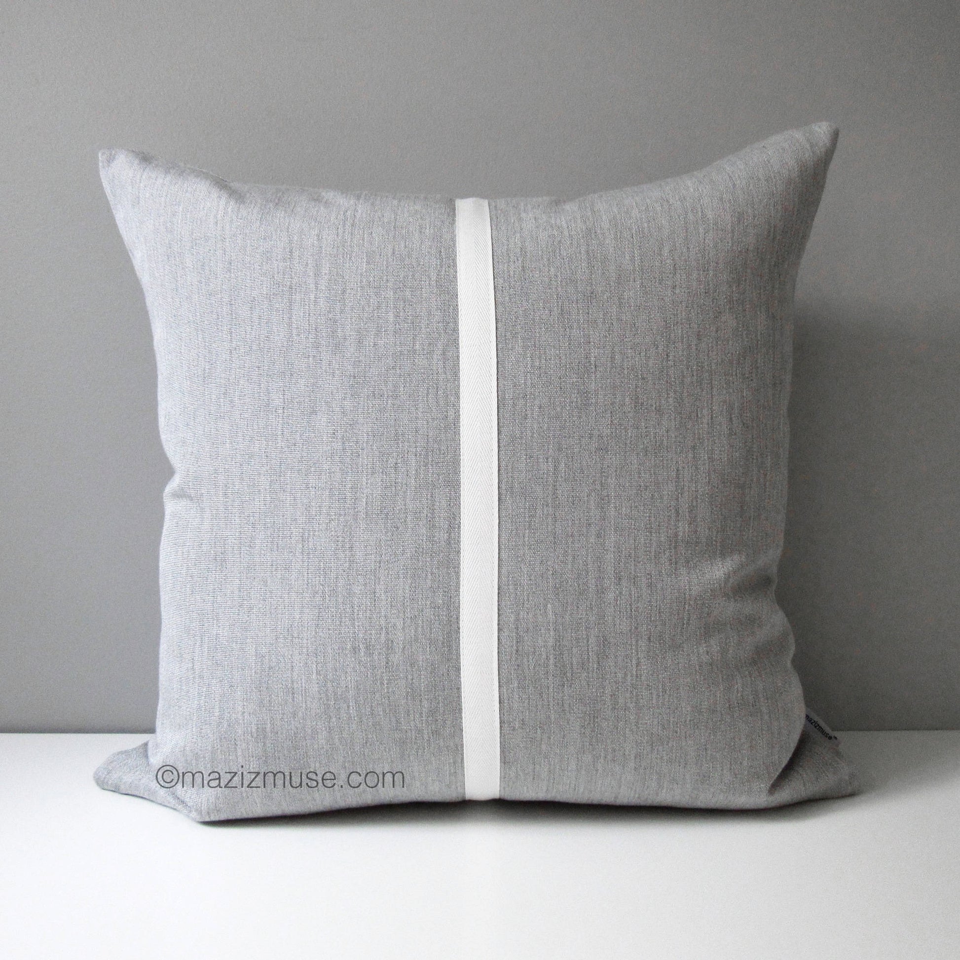 A light grey sunbrella pillow cover with a central white stripe detail, displayed against a neutral background.